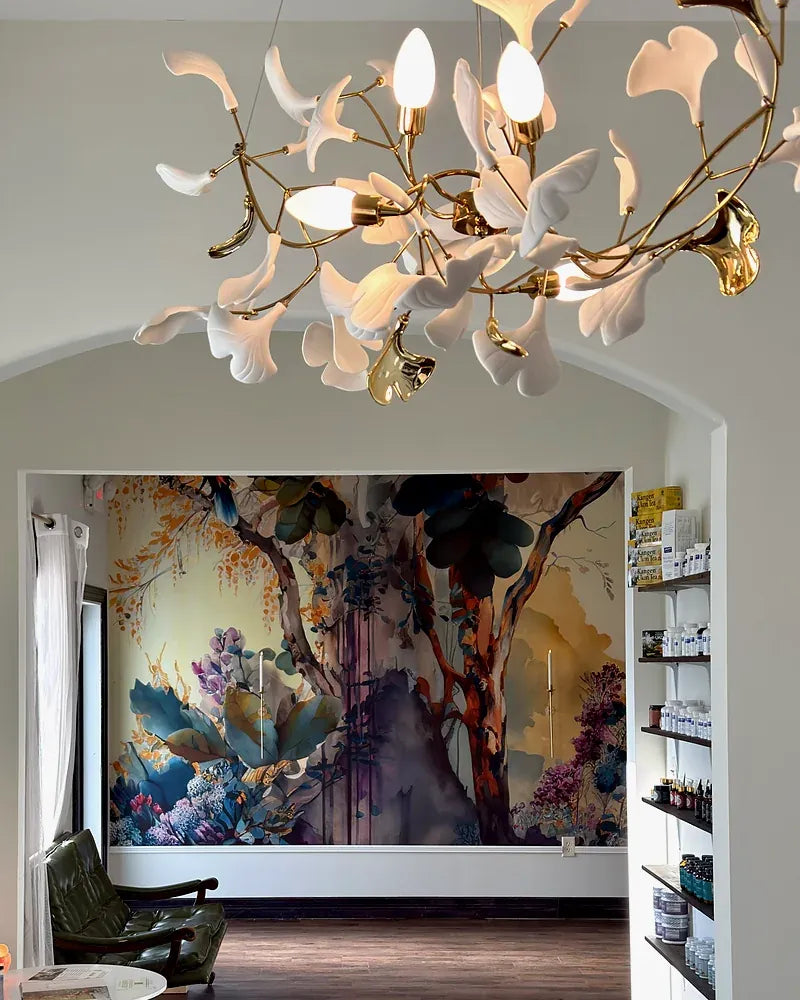 Inside the Zoi Well clinic in Buda: a ginkgo-leaf chandelier and a painted forest mural seen through an arched doorway